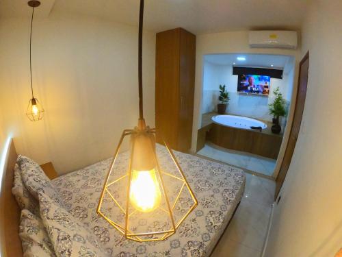 1 dormitorio con 1 cama y baño con bañera en TH 101 - Flat com Banheira de Hidromassagem en Governador Valadares