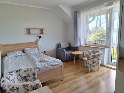 a bedroom with a bed and a chair and a window at Posiadłość Nad Zatoką in Ryn