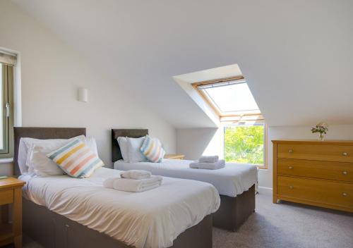 two beds in a room with a window at Chapel Cottage in Hempstead