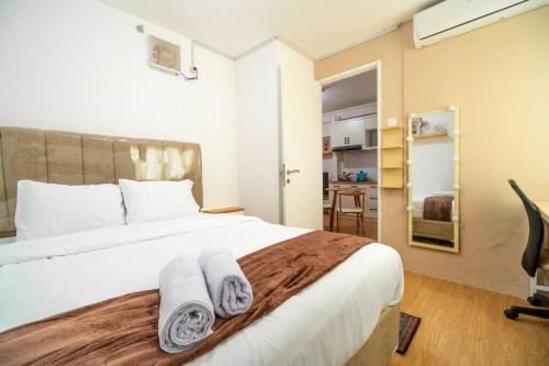 ジャカルタにあるElegance 2BR @ Bassura City East Jakarta /Netflixのタオルが敷かれたベッドのある寝室