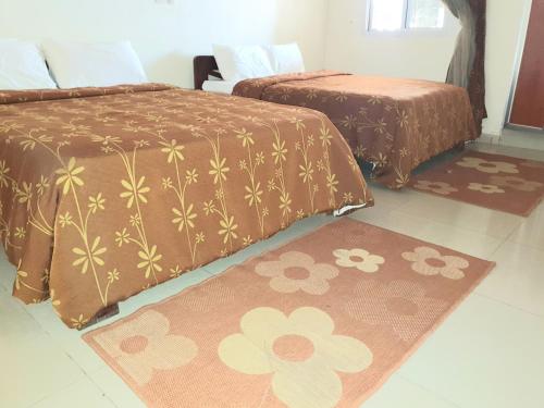 two beds in a room with two rugs on the floor at Hotel du Golfe de Guinee in Conakry