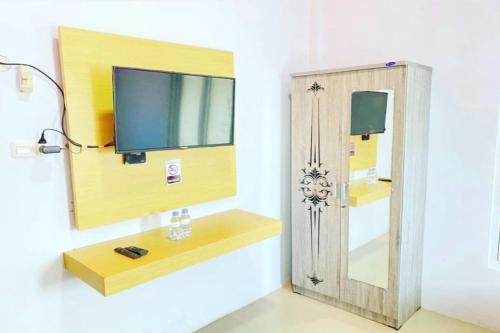 Habitación con espejo y TV en la pared. en OYO 93052 Batodupi Guesthouse Syariah, 