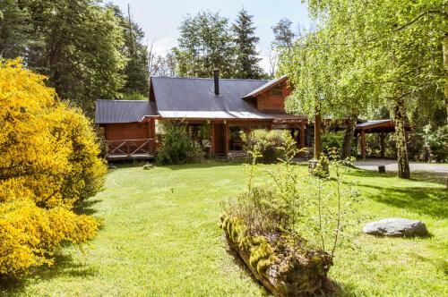 una cabaña de madera con un patio delante en BOG Arken - Casa junto al río en Villa La Angostura