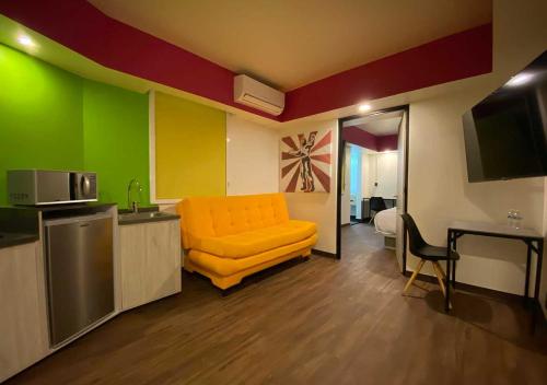 a living room with an orange couch and a kitchen at Estancias VIVE MX cuauhtémoc in Mexico City