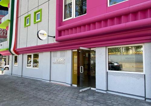 a pink building with a doorway on a street at Estancias VIVE MX cuauhtémoc in Mexico City