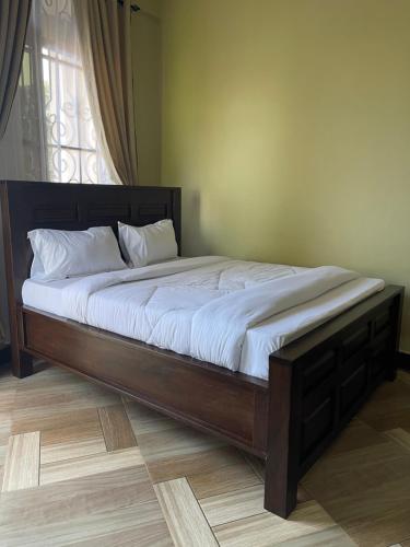 a large bed with a wooden frame in a bedroom at Skill forest lodge in Arusha
