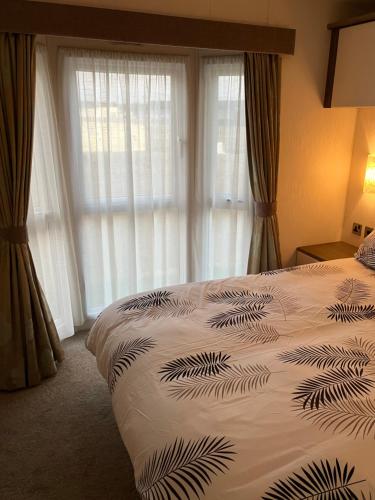 a bedroom with a bed and a large window at Staycay Luxury Caravan in Seasalter