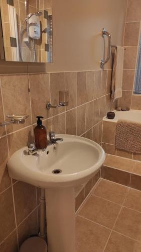 ein Badezimmer mit einem weißen Waschbecken und einer Dusche in der Unterkunft Retreat by the Feale in Listowel