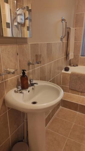 a bathroom with a white sink and a shower at Retreat by the Feale in Listowel