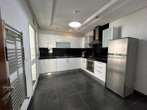 a kitchen with white cabinets and a stainless steel refrigerator at cosy et spacieux, avec balcon in Ariana