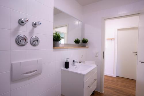 a white bathroom with a sink and a mirror at Design Apartment - Balkon - Induktionskochfeld - Zentral in Dresden