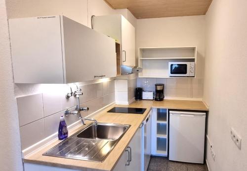 uma pequena cozinha com um lavatório e um micro-ondas em City Apartments em Neuss