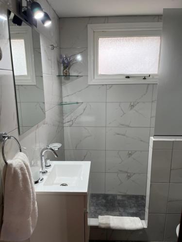 Baño blanco con lavabo y espejo en El Horreo Apart en Villa Gesell