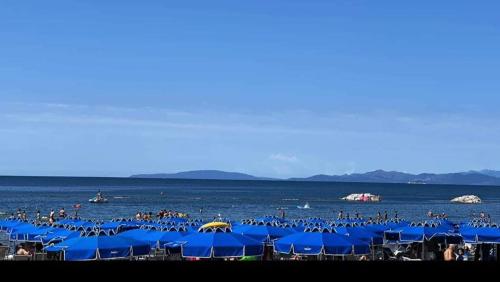 a beach with blue umbrellas and people in the water at Hausemaremma 1 camera in Follonica