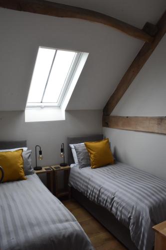 een slaapkamer op zolder met 2 bedden en een dakraam bij Cowshed in the Black Mountains in Abergavenny
