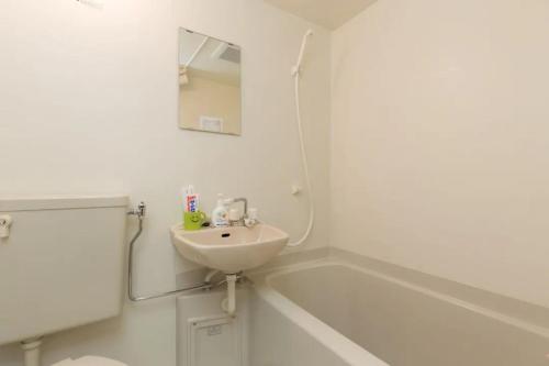 uma casa de banho branca com um lavatório e uma banheira em HOTEL LUCKY - Vacation STAY 49954v em Osaka