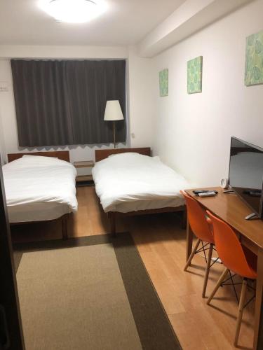 大阪市にあるHOTEL LUCKY - Vacation STAY 49954vのベッド2台、デスク、コンピュータが備わる客室です。