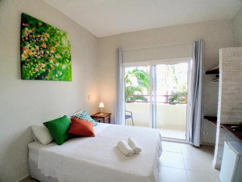 a bedroom with a white bed with a large window at Kauano Pousada Barequeçaba in São Sebastião
