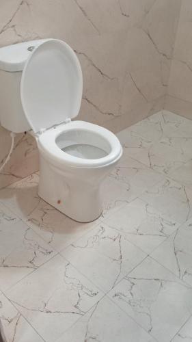 a white toilet in a bathroom with a marble floor at Amarula Tree Hotel in Mikumi