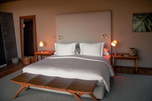 a large white bed in a bedroom with two lamps at Botanique Hotel Experience - Campos do Jordão in Campos do Jordão