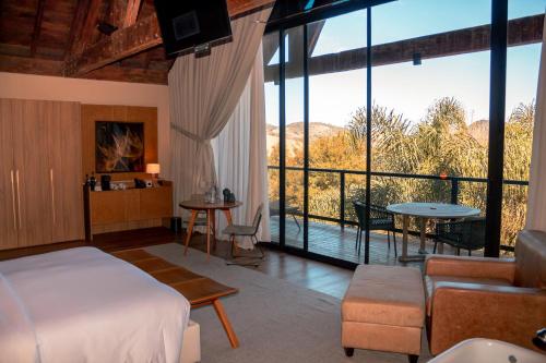 1 dormitorio con 1 cama y una gran ventana de cristal en Botanique Hotel Experience - Campos do Jordão, en Campos do Jordão