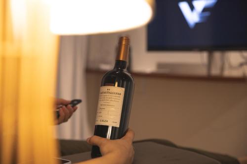 a person holding up a bottle of wine at Pousada Calza - Vale dos Vinhedos - Bento Gonçalves in Bento Gonçalves