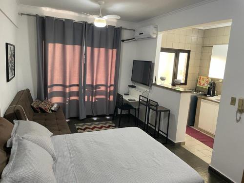 a bedroom with a bed and a kitchen with a desk at Ravena 016 in Ribeirão Preto