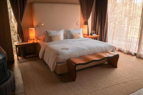 a bedroom with a large bed with a large window at Botanique Hotel Experience - Campos do Jordão in Campos do Jordão