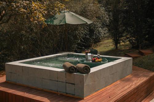 a hot tub with a plate of fruit and an umbrella at Botanique Hotel Experience - Campos do Jordão in Campos do Jordão