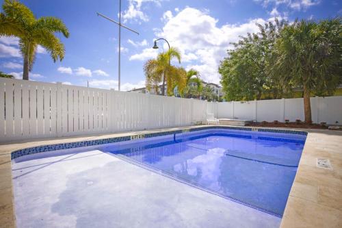 a swimming pool with a white fence and palm trees at La Mer Suites in Fort Lauderdale