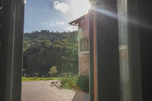 a view from a window of a building with the sun shining at Pousada Calza - Vale dos Vinhedos - Bento Gonçalves in Bento Gonçalves