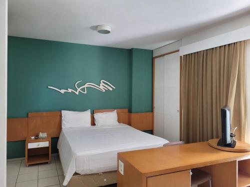 1 dormitorio con 1 cama y escritorio con TV en Praia do Canto Apart Hotel - Apto 405 - Varanda Lateral com Vista Mar, en Vitória