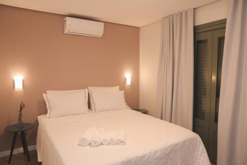 a bedroom with a white bed with two towels on it at Pousada Calza - Vale dos Vinhedos - Bento Gonçalves in Bento Gonçalves