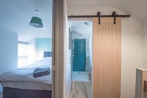 1 dormitorio con 1 cama y una puerta que conduce a una ducha en The Old Coach House, en Aberaeron