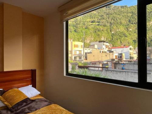 a bedroom with a window with a view of a city at Hospedaje Charlie's House in Baños