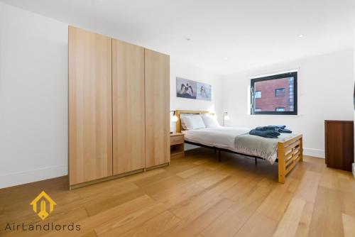 1 dormitorio con 1 cama y un gran armario de madera en Exclusive 2 Bedroom Flat near Buckingham Palace, en Londres