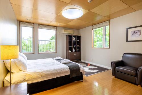 a bedroom with a bed and a chair and windows at Furano Chalet - Vacation STAY 14492 in Furano