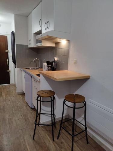 une cuisine avec deux tabourets de bar et un comptoir dans l'établissement *Le Super Land* Parking Privé * Cadre verdoyant*, à La Grande Motte