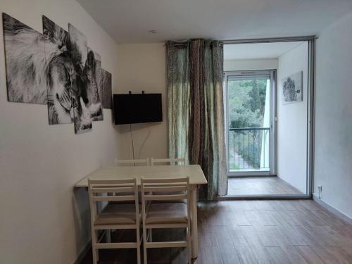une salle à manger avec une table et des chaises et une fenêtre dans l'établissement *Le Super Land* Parking Privé * Cadre verdoyant*, à La Grande Motte