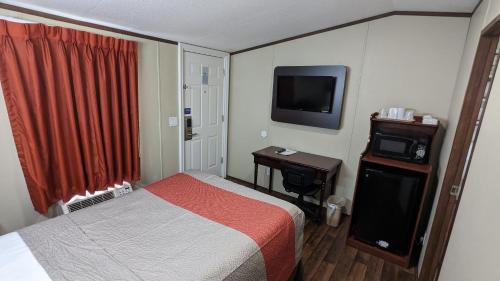 a hotel room with a bed and a television at Hillcrest Inn & Suites Ozona in Ozona