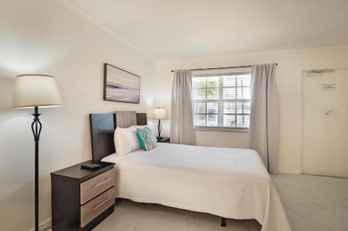 a white bedroom with a large bed and a window at La Mer Suites in Fort Lauderdale