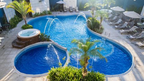 - une grande piscine avec une fontaine dans un complexe dans l'établissement Nadai Confort Hotel e Spa, à Foz do Iguaçu