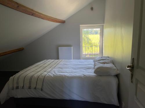 ein weißes Bett in einem Zimmer mit Fenster in der Unterkunft Belle vue in Saint-Silvain-Bas-le-Roc