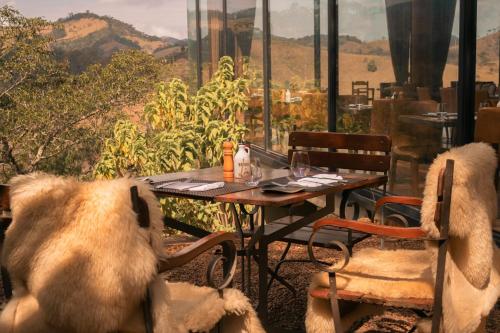 a table and chairs with a view of the mountains at Botanique Hotel Experience - Campos do Jordão in Campos do Jordão