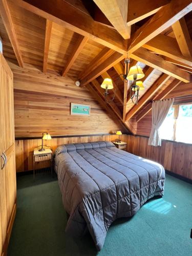 um quarto com uma cama grande num quarto de madeira em Apartamentos céntricos en San Martin de los Andes. em San Martín de los Andes