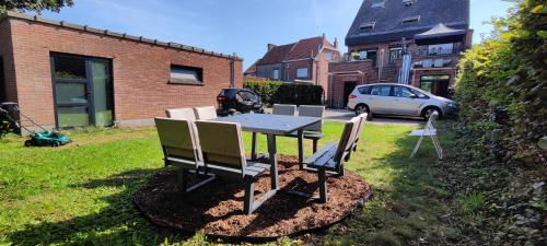 a table and chairs in a yard with a car at Logeerkamer XXL 25 m2 in Zemst