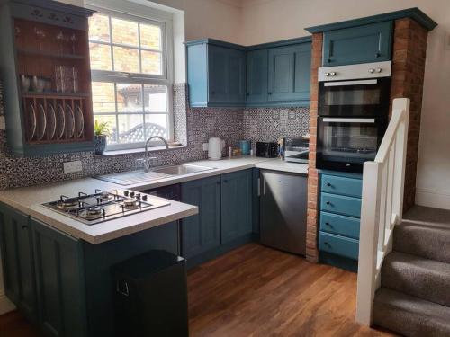 a kitchen with blue cabinets and a stove top oven at Number One Bridgefoot Cottage in West Stockwith