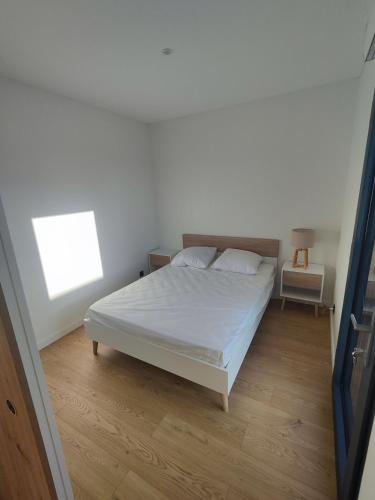 une chambre avec un lit blanc et un parquet dans l'établissement Domaine du Moulin Neuf aux portes de Beauval, à Nouans-les-Fontaines