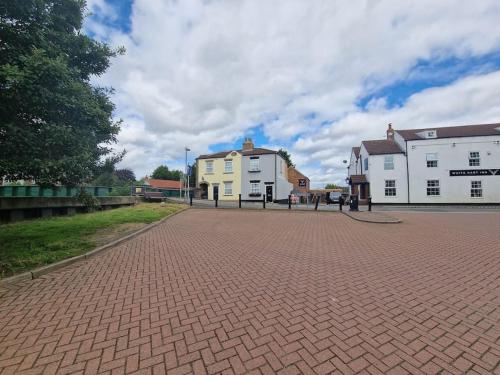 a brick parking lot with two white buildings and a street at Number One Bridgefoot Cottage in West Stockwith