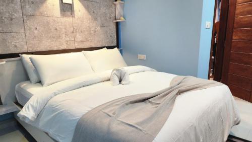 Isle inn في Fuvahmulah: غرفة نوم بسرير ذو شراشف ووسائد بيضاء
